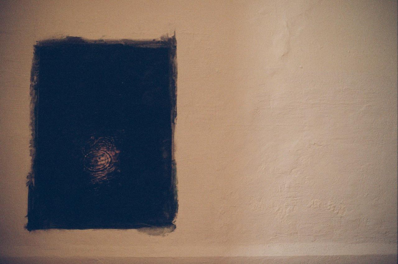 Un cuadro azul oscuro pintado sobre una pared de cal, con una espiral marcada en el centro